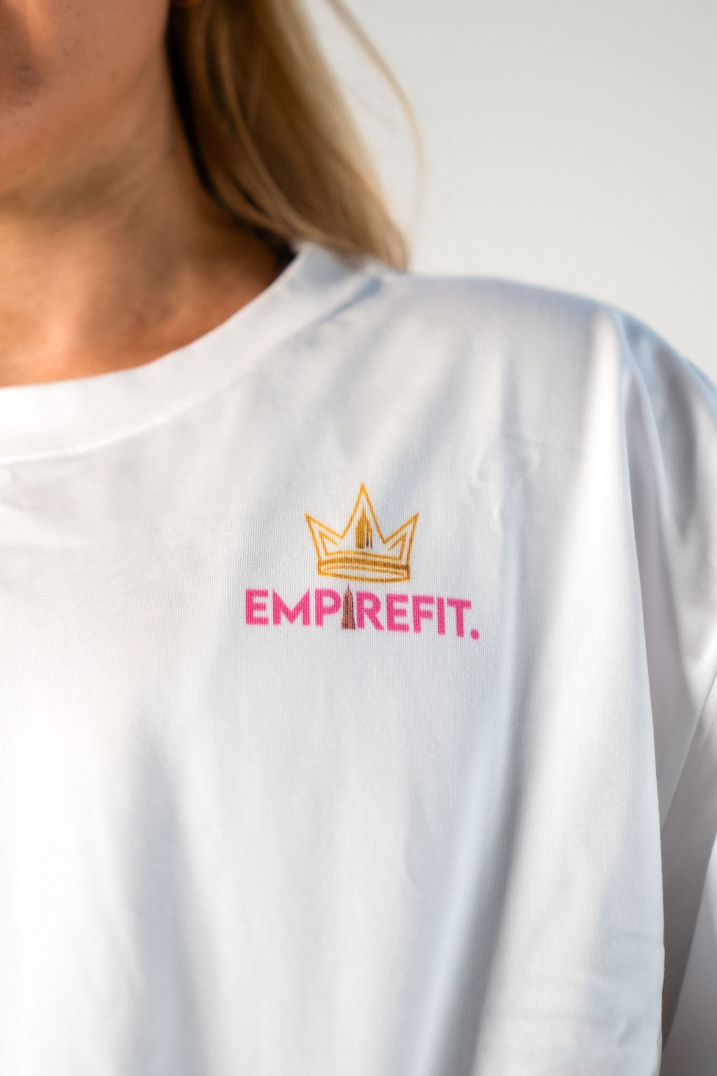 Close-up of the Empire Fit crown logo on the pink Claim Your Crown Tee relaxed fit gym t-shirt