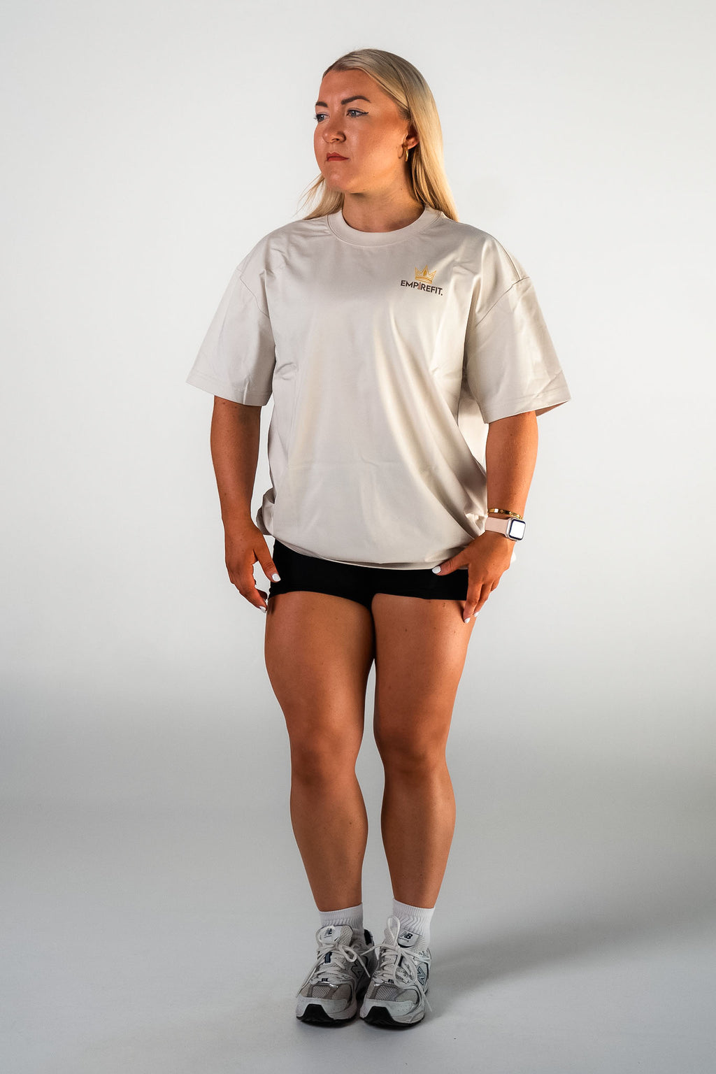 Female athlete walking wearing the beige Essentials Crown Tee relaxed fit gym t-shirt by Empire Fit