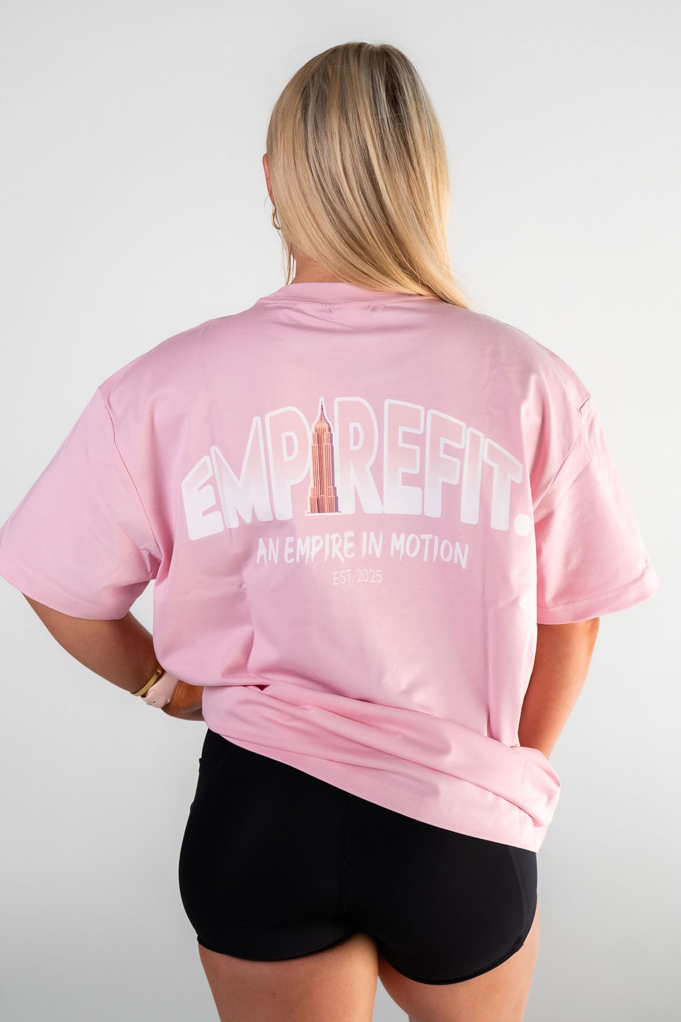Female athlete wearing the blush Empire in Motion Tee by Empire Fit back graphic