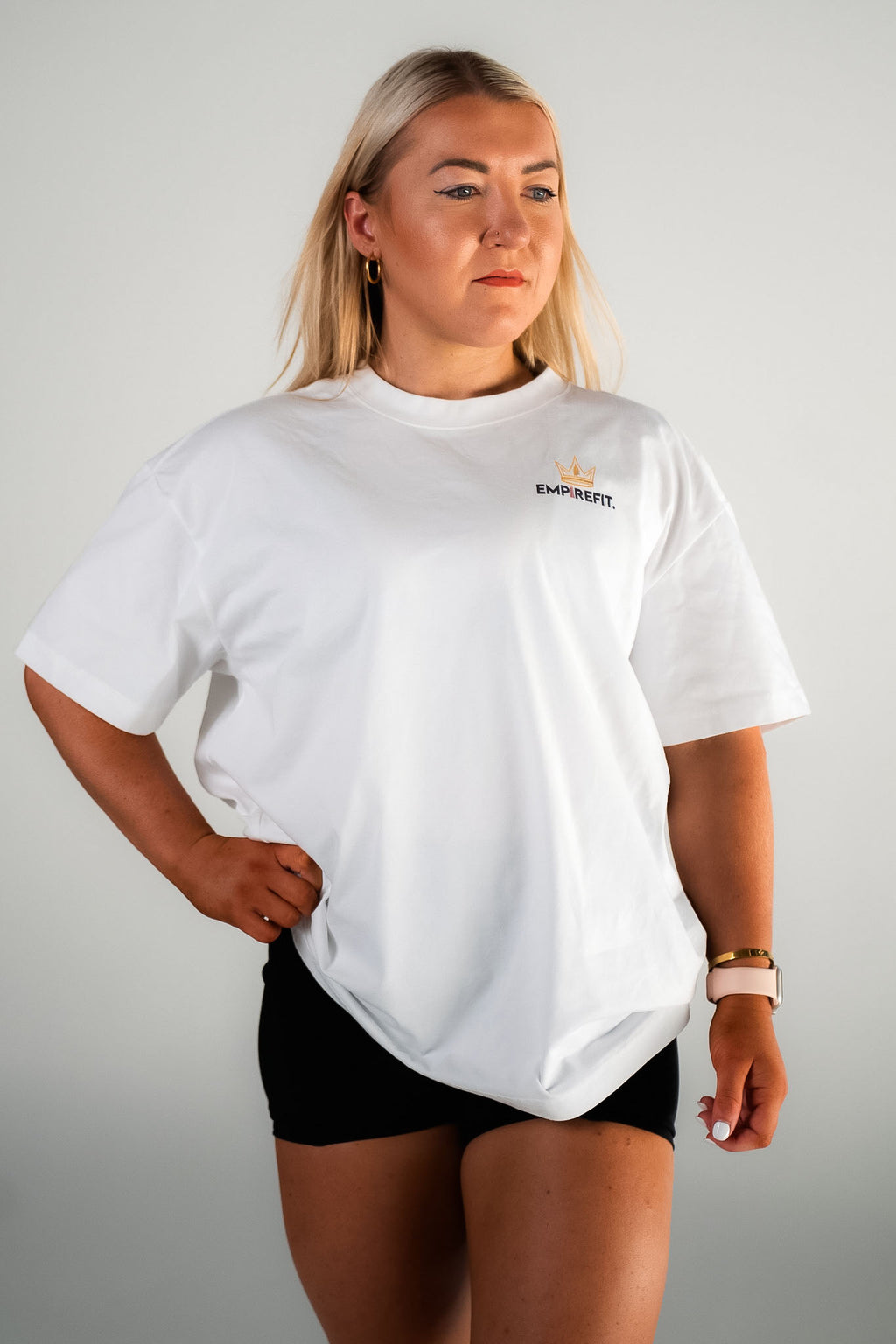 Female model wearing the white and black Claim Your Crown Tee relaxed fit gym t-shirt by Empire Fit